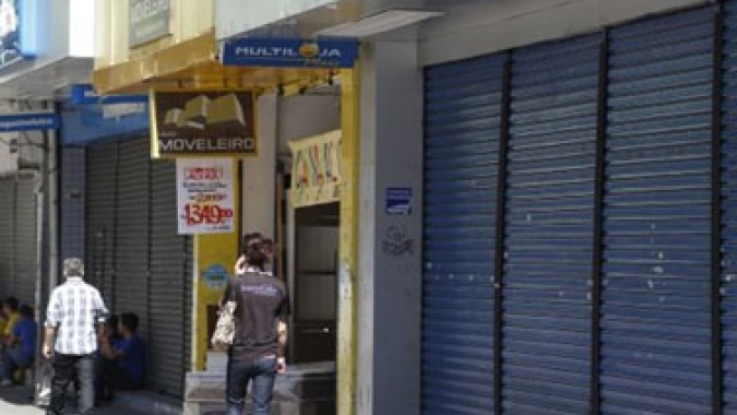 Pequenos comércios funcionam com as portas fechadas (ou abaixadas) em SP